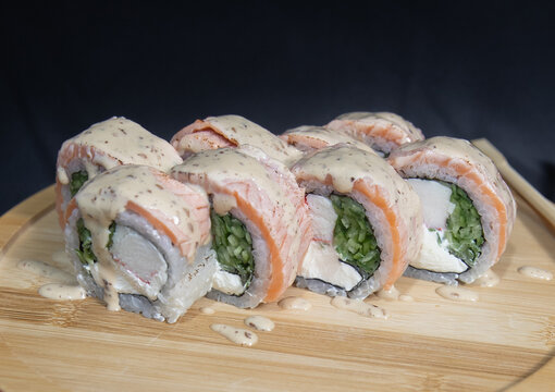 Sushi roll with salmon, cheese and avocado. Maki roll with shrimps fried, avocado and lattuce on a wooden plate . Delicious sushi rolls served on grey table