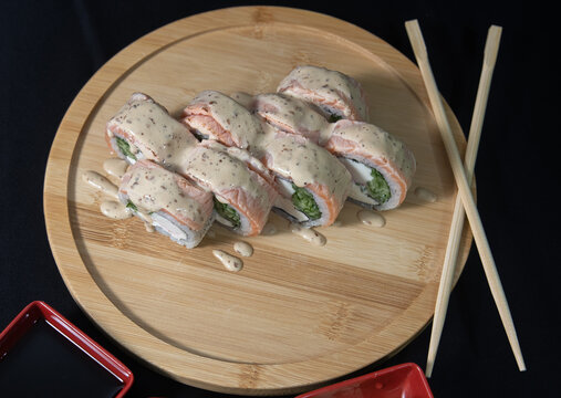 Sushi roll with salmon, cheese and avocado. Maki roll with shrimps fried, avocado and lattuce on a wooden plate . Delicious sushi rolls served on grey table