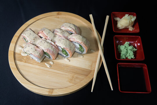 Sushi roll with salmon, cheese and avocado. Maki roll with shrimps fried, avocado and lattuce on a wooden plate . Delicious sushi rolls served on grey table