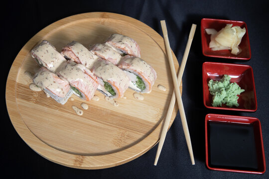 Sushi roll with salmon, cheese and avocado. Maki roll with shrimps fried, avocado and lattuce on a wooden plate . Delicious sushi rolls served on grey table