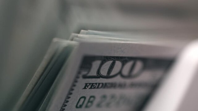 One hundred dollar banknotes being processed in modern counting machine. Banking concept.
