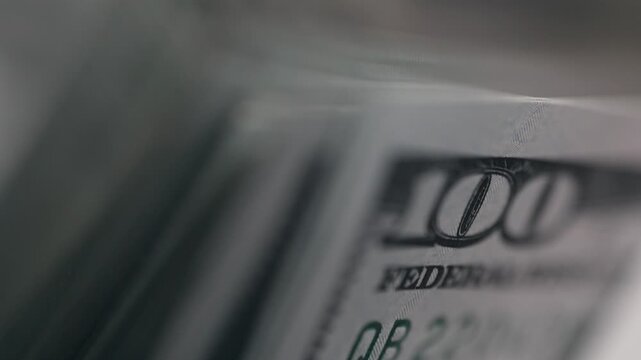 Close-up sequence of hundred-dollar bills fanned out, showcasing intricate details of currency design and texture against a blurred background in a financial context