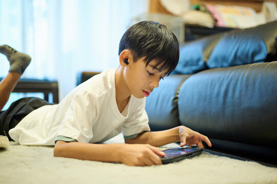 床でスマホゲームをする男の子