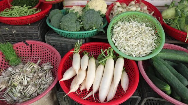 Fresh White Radish And Cucumber Display In Vietnam Street Market, Red And Green Plastic Baskets With Broccoli, Bean Sprouts And Long Cucumbers, Quiet Morning Stall Atmosphere, Vibrant Produce