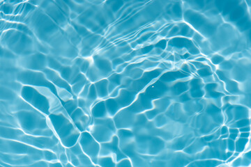 Fototapeta premium Blue water with ripples on the surface. Defocus blurred transparent blue colored clear calm water surface texture with splashes and bubbles. Water waves with shining pattern texture background.