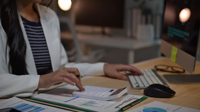 Businesswoman performs calculations and enters data into computer