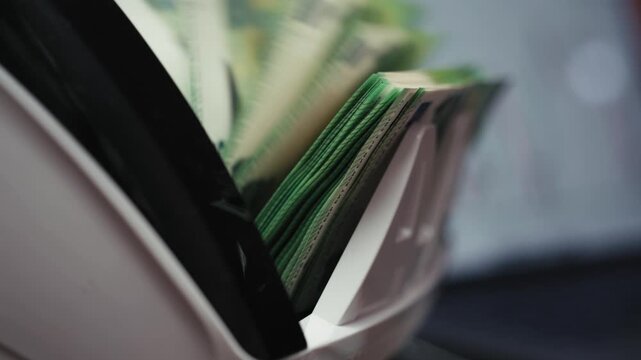 Female accountant counting cash in counting machine with analytics dashboard on laptop. Business concept.
