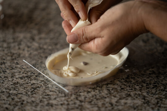 Manos colocando chocolate blanco en molde pl&aacute;stico, preparaci&oacute;n de dulces de Pascua en primer plano