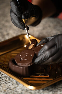 Manos decorando conejo de chocolate con brillo dorado en proceso de reposter&iacute;a, fotograf&iacute;a gastron&oacute;mica macro
