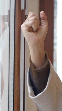 Close up shot of hand turning window handle to open it during daytime