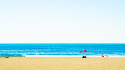 Fototapeta premium Woman standing by the waterfront looking out over a calm blue ocean under a bright sky, enjoying a peaceful coastal view in a seaside city. 