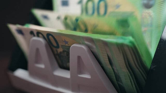 Close-up of one hundred euro bills in automatic money counting machine. Banking and finance concept.

