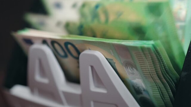 Close-up sequence of cash in a wallet showing multiple banknotes with visible denominations, highlighting the flow of currency in a financial context