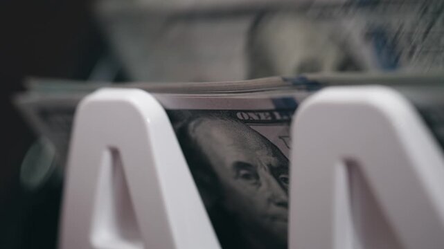 Close-up view of stacked U.S. dollar bills in a white money holder, showcasing the detailed design and texture of the currency in a focused arrangement