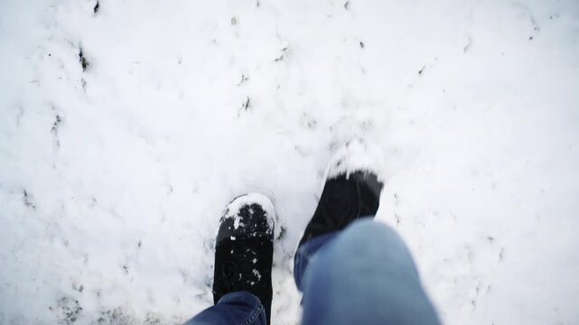 Point of view shot of winter boots standing on icy ground with snow patches