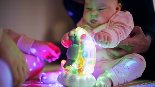 Close up of infant touching illuminated toy with colorful lights during playtime