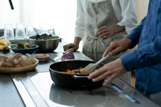料理をする日本人シニア夫婦の手元