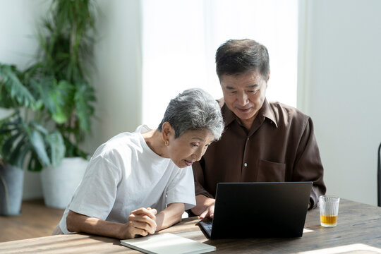 ノートパソコンを見る日本人シニア夫婦