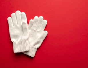 Obraz premium White knit gloves on red background