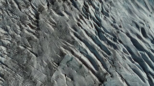 Blue glacier surface with deep cracks and striations with debris patches, Norwegian mountains, Norway