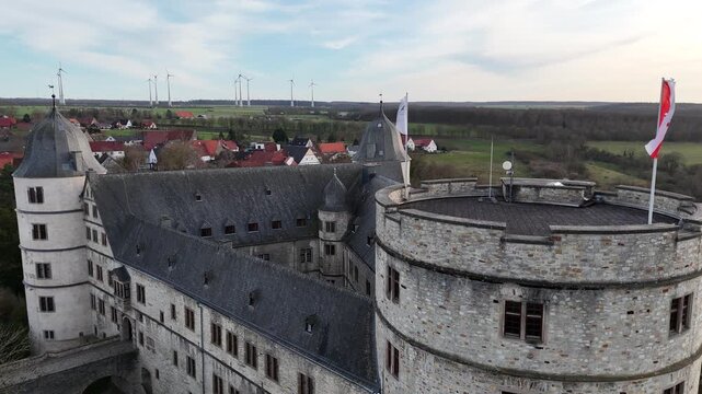 Static drone shot near the tower captures waving flags from a close side perspective against the sky.