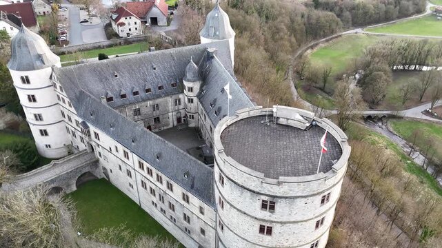 Drone glides slowly toward the tower while the camera tilts upward to reveal courtyard village and horizon.