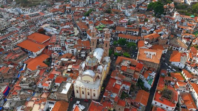 Aerial view of the Santa Prisca temple with viceroyalty architecture surrounded by white colonial houses with tiled roofs, Taxco, Guerrero, Mexico