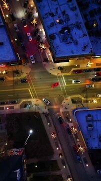 A vertical top-down aerial shot capturing La Grange, Illinois, a busy city intersection at night with moving cars, streetlights, and festive decorations.
