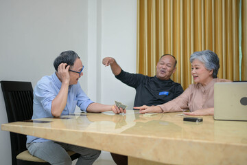 Fototapeta premium Group of mature friends playing cards together at a table