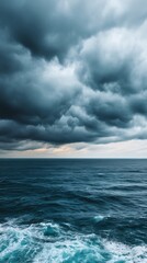 Fototapeta premium Dark storm clouds gather above a turbulent ocean, creating a dramatic and moody seascape with waves crashing under an overcast sky.