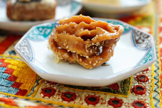 Close-up of Chebakia, a traditional Moroccan honey cookie with sesame seeds, on an ornate plate