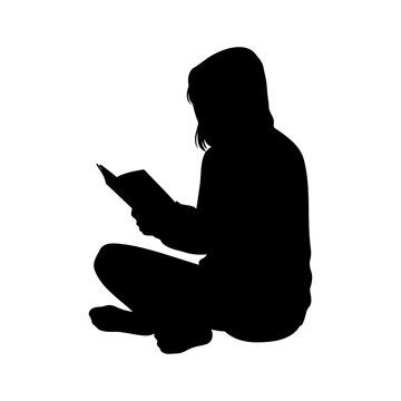 Silhouette of a young girl sitting cross-legged on the floor and reading a book