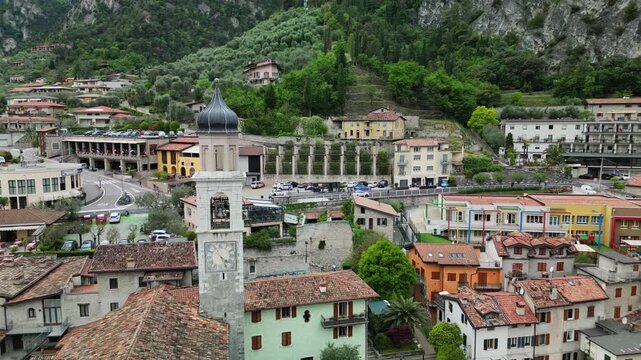 Drone aerial view of San Benedetto church and historic center of Limone sul Garda on Lake Garda, Italy, with traditional houses and mountains rising above the town.