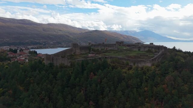 Drone reveals Samuil Fortress atop the hill in Ohrid, gradually showing the old waterside town and Lake Ohrid, highlighting medieval architecture and scenic Balkan landscapes.
