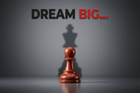 Wooden pawn casting shadow of chess king and text dream big on gray background