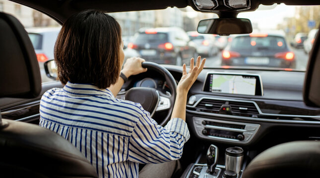 Woman driver stuck in heavy traffic, expressing clear frustration with an exasperated hand gesture.