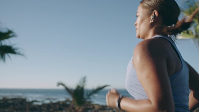 Woman, fitness and running with earphones or music on ocean coast or promenade for outdoor workout. Active, female person or runner with sprint or exercise for cardio training, health or wellness