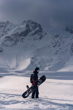 Snowboarder with snowboard against a mountain backdrop