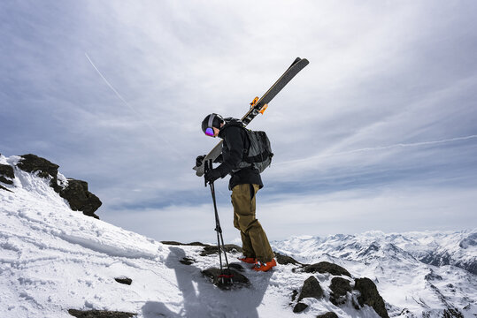 Skier hiking up a mountain with skis on his back