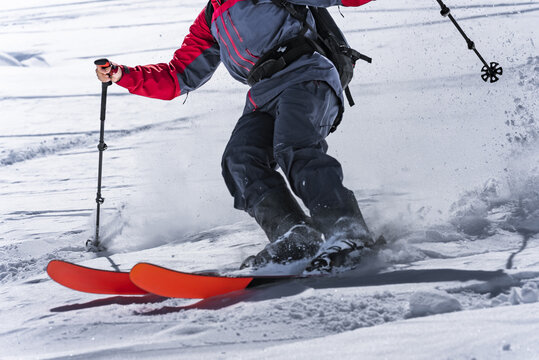 Close-up of a skier's legs and skis carving on a slope