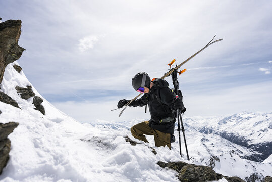 Skier hiking up a mountain with skis on his back