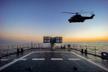 A helicopter flies over a warship during a naval exercise in mediterranean sea. © ValStock