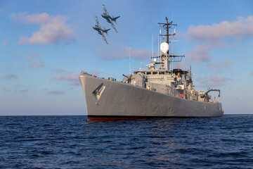 A pair of military aircraft fly over a warship during a mission in the Persian Gulf.  © ValStock