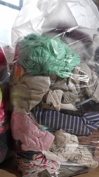 Piled bales of used childrens clothes and shoes representing global textile waste problem and overconsumption