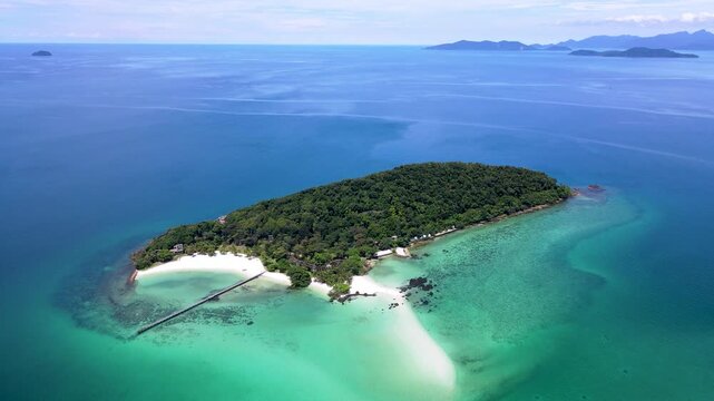 Experience the serene beauty of Koh Kham in Trat, Thailand, with its clear turquoise waters, soft sandy beaches, and lush greenery under a bright blue sky.