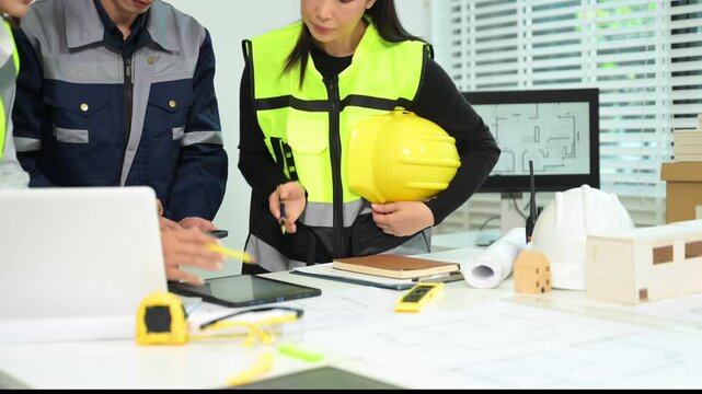 Engineer teams meeting working together wear worker helmets hardhat with on architectural project site and making model house. Asian industry professional team