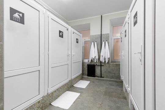 Modern Shared Hostel Bathroom with White Shower and Toilet Stalls