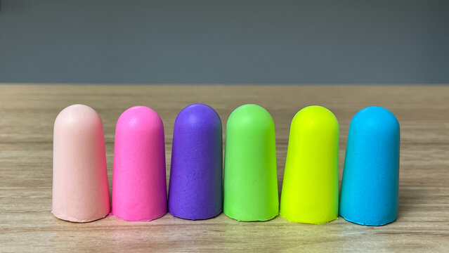 A set of brightly colored earplugs on a desk. Suitable for topics such as sleep, working in noisy environments, travel, and hearing care.