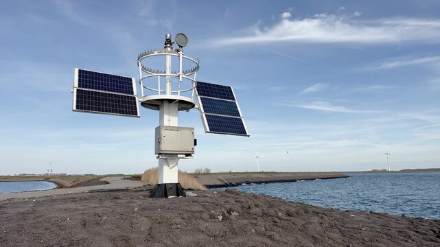 Wide landscape view of coastal research weather station with solar panels and anemometer, situated in Dutch wetland environment with water channels, dikes, wind turbines and flat horizon visible.