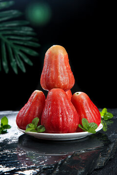 Fresh Ruby Red Wax Apples from Hainan with Mint Garnish on Dark Stone Surface